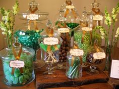 a table topped with lots of different types of candies and candy bar signs on top of glass containers