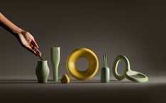 a person is touching the letters made out of different colored vases and cups that are stacked on top of each other