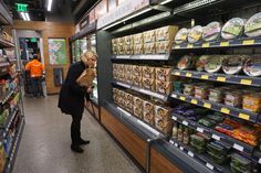 a woman is looking at food in the store