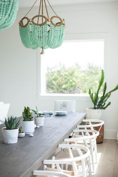 a dining room table with chairs and green beaded chandelier hanging from the ceiling