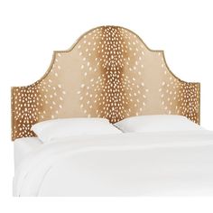 an upholstered headboard on a bed with white sheets and pillows, in front of a white background