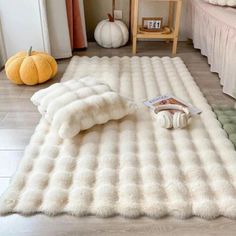 a large white rug in the middle of a room with pumpkins on the floor