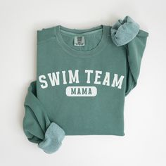 a green shirt with the words swim team on it and a blue mitt next to it