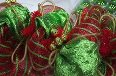 green and red christmas decorations on display in front of a white background with gold trim