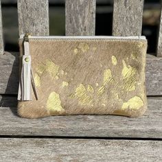 This Fleuri makeup bag / mini clutch is a great versatile little bag that is perfect for your phone, credit card and keys or to use as a stylish makeup bag. This makes a great 'grab and go' purse!  Dimensions: Height: 12cm (4.7in) Width: 20.5cm (8in) Flat construction The Fleuri clutch is made from metallic gold cowhide on both sides and has a cream, starry cotton lining on the inside. It is a flat construction, with a pretty YKK gold colour zip with a cream leather tassel pull. PLEASE NOTE; we cannot deliver to Germany. Delivery is via Royal Mail  first class for UK buyers and Standard International Delivery (3-7 business days) for elsewhere. Should you need your purchase sooner please contact me before ordering. Many of my bags have stone quarrying names (like the Fleuri!) reflecting the Gold Clutch Purse, Cowhide Clutch, Printed Leather Bag, Gold Evening Bag, Cowhide Purse, Stylish Makeup, Cowhide Bag, Card Purse, Gold Clutch