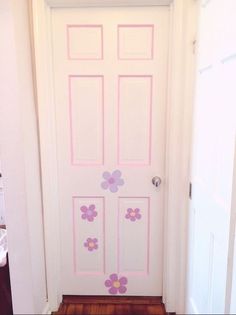 a white door with pink and purple flowers painted on the front side, along with a brown wooden floor