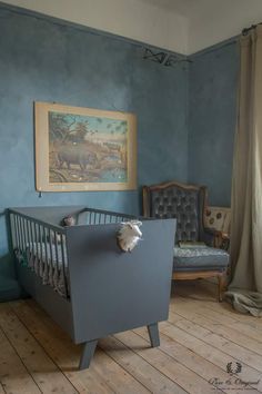 a baby's crib in the corner of a room with blue walls and wooden floors