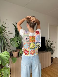 a woman standing in front of a plant and wearing a granny granny sweater over her shoulders