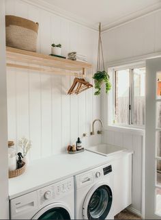 a washer and dryer in a white laundry room with open shelving on the wall