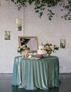 a table topped with a cake and flowers next to a framed photo on a wall