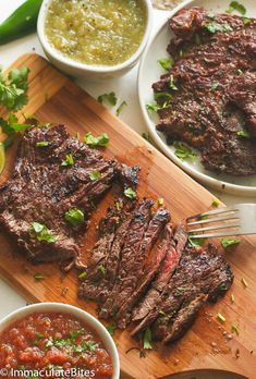 steak with salsa and green beans on a cutting board next to two bowls of salsa