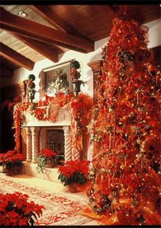 a decorated christmas tree sitting in front of a fire place with red poinsettias