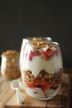 a dessert in a glass with strawberries and granola