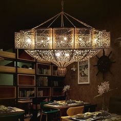 a chandelier hanging from the ceiling in a dining room with tables and chairs