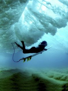 a person on a surfboard in the water under a large wave with white foam