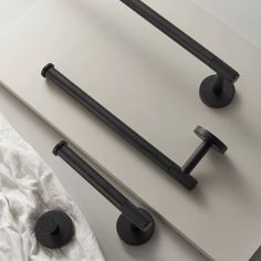 two black handles on the back of a white counter top next to a towel rack