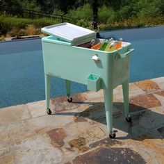 a cooler sitting on top of a stone floor next to a swimming pool