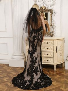 the back of a woman in a black wedding dress with a veil on her head