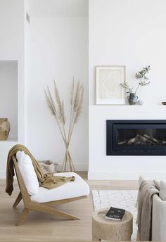 a living room with white furniture and a fire place in the corner, including a chair