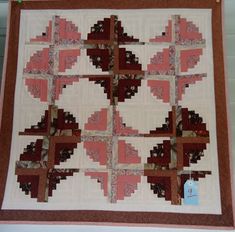 a quilted wall hanging on the side of a building with red and white squares