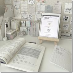 an open book sitting on top of a desk next to a computer monitor and books