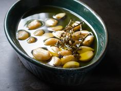 a green bowl filled with some kind of food on top of a wooden table next to a black surface