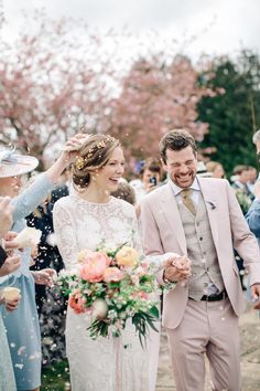 a bride and groom walk through confetti thrown by their guests