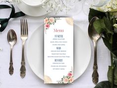 a white plate topped with a menu next to silverware and flowers on top of it