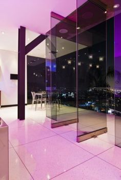 an empty room with glass walls and purple lighting in the corner, overlooking city lights