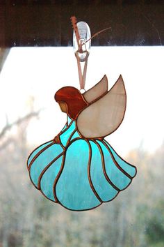 a stained glass angel ornament hanging from a window