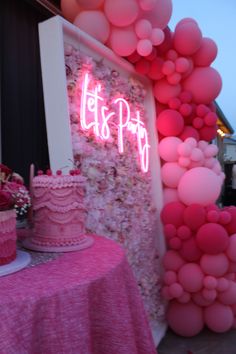 there is a pink cake on the table with balloons in the background and a sign that says it's pip