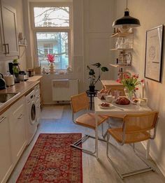 a kitchen with a table and chairs in front of a window next to a sink