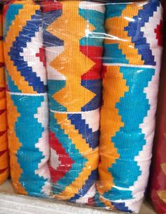 several rolls of colorful fabric sitting on top of a shelf