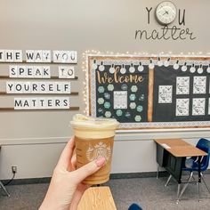 a person holding up a cup of coffee in front of a chalkboard with the words you matter