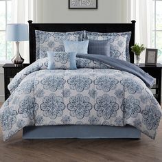 a bed with blue and white comforters in a bedroom next to two nightstands