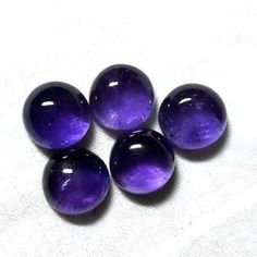 four purple marbles sitting on top of a white cloth