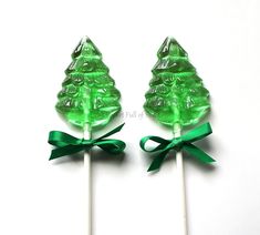 two green candy lollipops with bows on white background, one is shaped like a christmas tree