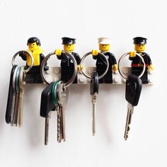 four lego keychains are attached to the wall with keys in each one's hands