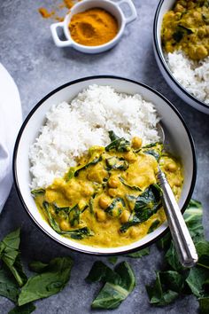 two bowls filled with rice, spinach and curry