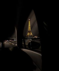 the eiffel tower seen through a car's rear view mirror at night