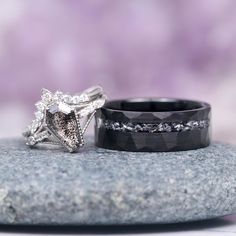 two wedding rings sitting on top of a rock next to each other with diamonds in them