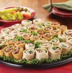 a platter filled with sandwiches on top of a table next to plates of food