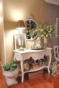 a white table with flowers on it and a mirror in the corner next to it