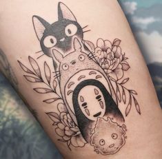 a black and white tattoo with a cat on it's thigh next to flowers