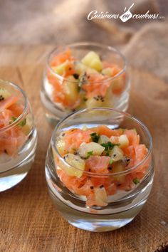 three small glass bowls filled with food on top of a wooden table next to each other