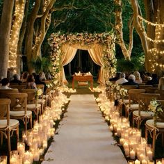 an outdoor wedding ceremony with candles lit up in the trees and flowers on the aisle