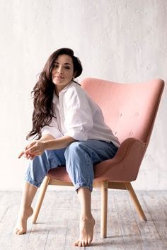 a woman is sitting on a pink chair