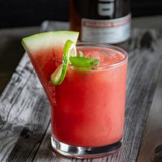 a watermelon drink with a slice of cucumber and mint garnish