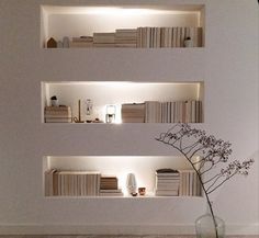 a vase filled with flowers sitting on top of a wooden floor next to bookshelves