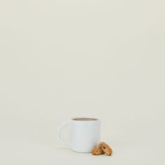 a white coffee cup with some cookies on the side